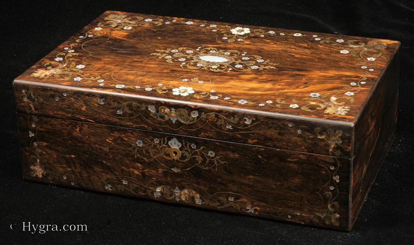 Exquisite figured coromandel profusely inlaid with  engraved brass, mother of pearl, and abalone depicting trailing flowers. by  S. Woolfield 28 Bucanan St., Glasgow. Inside the embossed blue velvet writing surface is framed with gold embossed leather and rosewood. beneath one of the flaps there is a compartmentalized liftout tray still covered in its original paper. The lock is Bramah type and stamped "Bramah Patent and a crown. The escutcheon is flush with the surface. circa 1860. Enlarge Picture